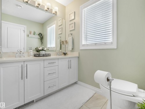 Double vanity featuring a light-toned countertop, dual undermount sinks, and white cabinetry with brushed nickel hardware - 283 Ameena Drive, Leduc, AB - Indoor Photo Showing Bathroom