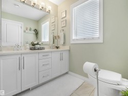 Double vanity featuring a light-toned countertop, dual undermount sinks, and white cabinetry with brushed nickel hardware - 