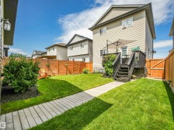 Private fenced backyard with a paver pathway, green lawn, a dark-stained deck, and a wood fence - 