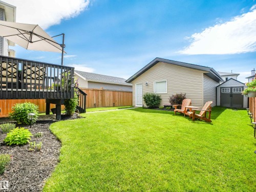 Spacious backyard featuring a large elevated deck, a detached garage, a storage shed, a manicured lawn, and perimeter wood fencing - 283 Ameena Drive, Leduc, AB - Outdoor