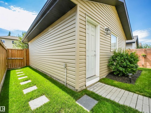 Detached garage featuring light-colored horizontal siding, a white entry door, and an exterior wall light - 283 Ameena Drive, Leduc, AB - Outdoor With Exterior