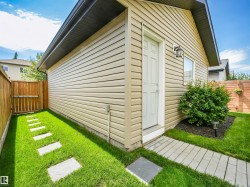 Detached garage featuring light-colored horizontal siding, a white entry door, and an exterior wall light - 