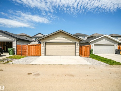 Detached garage with a light beige overhead door, concrete driveway, and gravel border - 283 Ameena Drive, Leduc, AB - Outdoor