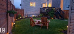 Expansive backyard featuring a manicured lawn, established landscaping, and a multi-level deck with dark wood railing - 