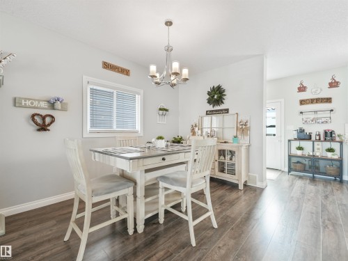 Open-concept dining area featuring wood-finish flooring, light gray wall paint, and a modern chandelier - 283 Ameena Drive, Leduc, AB - Indoor Photo Showing Dining Room