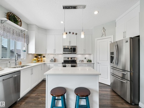 Kitchen featuring white shaker cabinetry, stainless steel appliances, a center island, white subway tile backsplash, and wood-finish flooring - 283 Ameena Drive, Leduc, AB - Indoor Photo Showing Kitchen With Double Sink With Upgraded Kitchen