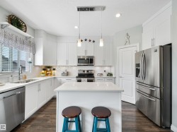 Kitchen featuring white shaker cabinetry, stainless steel appliances, a center island, white subway tile backsplash, and wood-finish flooring - 