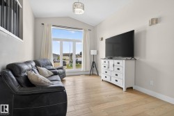 Living area featuring vaulted ceilings, light wood-finish flooring, and a large multi-pane window - 