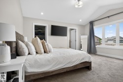 Vaulted ceiling bedroom featuring plush carpet flooring, recessed lighting, and a large multi-pane window with architectural trim - 