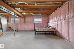 Unfinished basement space featuring exposed wood joists and subfloor, concrete flooring, and insulated walls - 