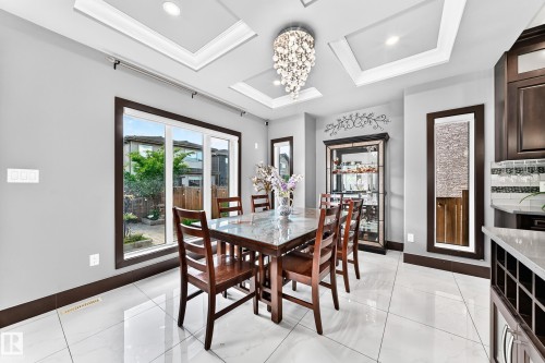 Formal dining area featuring coffered ceilings with recessed lighting, a chandelier light fixture, and large patio doors - 16244 138 Street Nw, Edmonton, AB - Indoor Photo Showing Dining Room