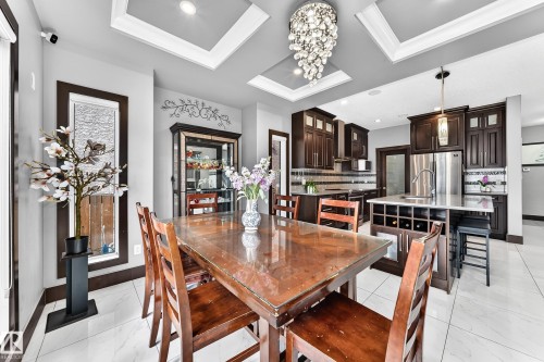 Dining area featuring tray ceilings with recessed lighting, a decorative chandelier, and large format tile flooring - 16244 138 Street Nw, Edmonton, AB - Indoor Photo Showing Dining Room