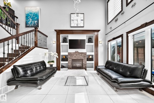 Vaulted ceiling living area featuring a stone-clad fireplace, integrated shelving, and large format white tile flooring - 16244 138 Street Nw, Edmonton, AB - Indoor With Fireplace