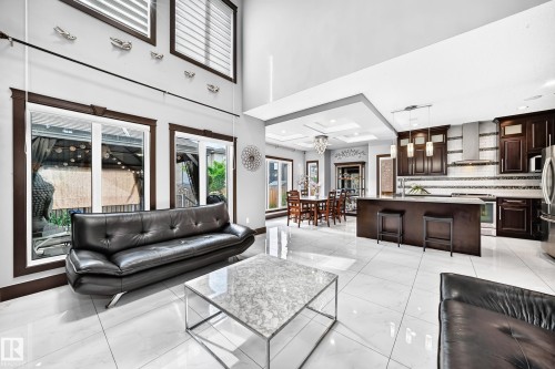 Open-concept living space featuring high ceilings, white tile flooring, and dark-framed windows - 16244 138 Street Nw, Edmonton, AB - Indoor