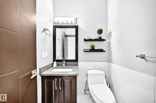 Powder room featuring a dark wood vanity with an integrated sink, framed mirror, and chrome faucet - 16244 138 Street Nw, Edmonton, AB - Indoor Photo Showing Bathroom