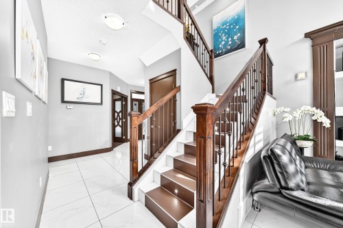 Grand foyer featuring a dual-level staircase with dark wood-finish treads, risers, and handrails, complemented by black wrought iron balusters - 16244 138 Street Nw, Edmonton, AB - Indoor Photo Showing Other Room