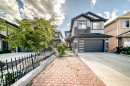 Two-story stucco and stone-clad residence featuring a modern garage door with frosted glass panels, a concrete driveway, and a paved walkway - 16244 138 Street Nw, Edmonton, AB  - Outdoor 