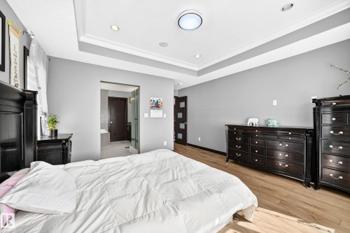 Spacious bedroom featuring wood-finish flooring, a tray ceiling with recessed lighting, and a neutral wall color - 16244 138 Street Nw, Edmonton, AB - Indoor Photo Showing Bedroom