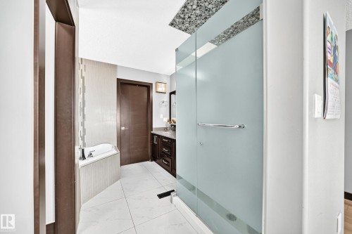 Contemporary bathroom featuring a frosted glass shower enclosure, white tile flooring, and a built-in corner soaking tub - 16244 138 Street Nw, Edmonton, AB - Indoor Photo Showing Bathroom
