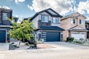 Two-story residence featuring a dark gray garage door with horizontal accents, a paved driveway, and a stone facade - 16244 138 Street Nw, Edmonton, AB  - Outdoor With Facade 