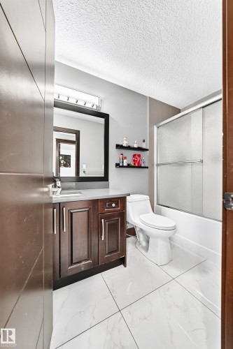 Bathroom featuring a dark wood vanity with a light countertop, a toilet, and a shower with a sliding glass door - 16244 138 Street Nw, Edmonton, AB - Indoor Photo Showing Bathroom