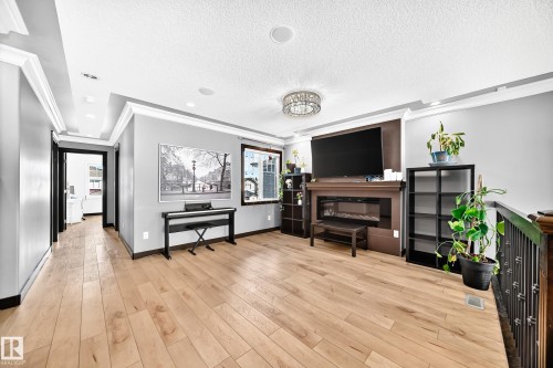 Spacious living area featuring wood-finish flooring, a built-in fireplace with a dark wood surround, and a coordinating dark wood accent wall - 16244 138 Street Nw, Edmonton, AB - Indoor