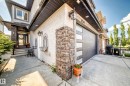 Stucco exterior with stone accents, featuring a modern garage door with frosted glass panels, a concrete driveway, and a front entry with a decorative glass door - 16244 138 Street Nw, Edmonton, AB  - Outdoor 