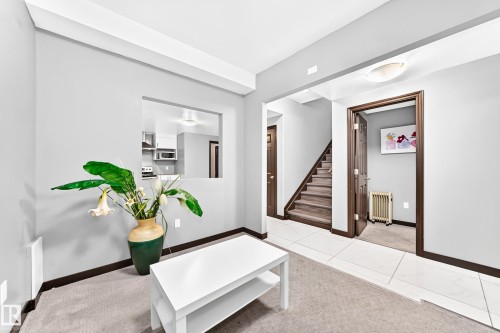 Living area featuring light gray walls, dark wood-finish trim, and a pass-through window looking into the kitchen - 16244 138 Street Nw, Edmonton, AB - Indoor Photo Showing Other Room