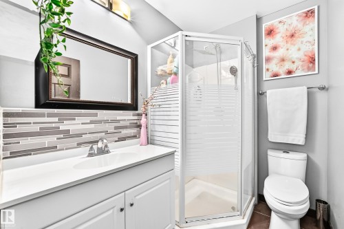 Bathroom featuring a glass-enclosed shower, white vanity with integrated sink, rectangular framed mirror, mosaic tile backsplash, and overhead vanity lighting - 16244 138 Street Nw, Edmonton, AB - Indoor Photo Showing Bathroom