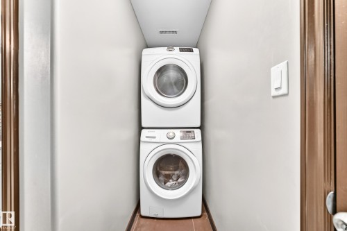 Dedicated laundry closet featuring a stacked white front-load washer and dryer - 16244 138 Street Nw, Edmonton, AB - Indoor Photo Showing Laundry Room