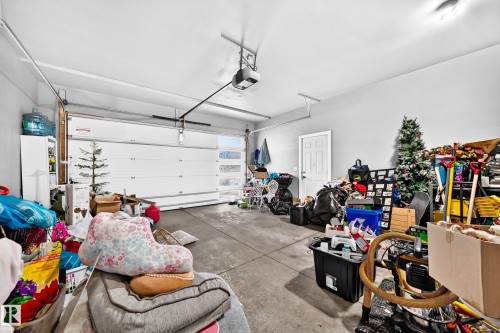 Integrated garage space featuring a paneled overhead door with frosted glass inserts, concrete flooring, and a side access door - 16244 138 Street Nw, Edmonton, AB - Indoor Photo Showing Garage