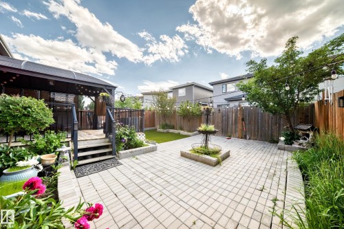 Spacious backyard featuring a large paver patio, elevated wood deck with a covered pergola, mature landscaping, fenced perimeter, and a central water feature - 16244 138 Street Nw, Edmonton, AB - Outdoor With Deck Patio Veranda