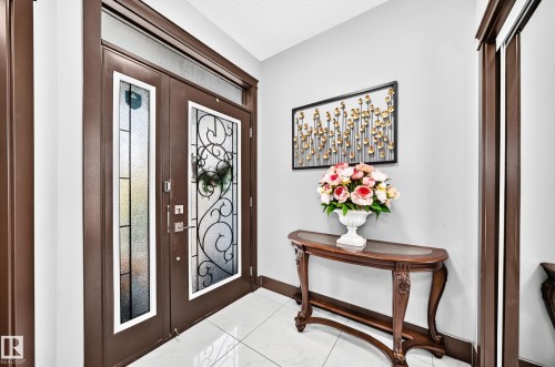 Double entry doors with decorative glass panels and a transom window, set within dark wood trim - 16244 138 Street Nw, Edmonton, AB - Indoor Photo Showing Other Room