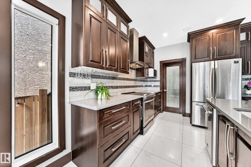 Modern kitchen featuring rich wood-finish cabinetry and stainless steel appliances - 16244 138 Street Nw, Edmonton, AB - Indoor Photo Showing Kitchen With Upgraded Kitchen