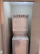 Dedicated laundry closet featuring a white stacked washer and dryer unit - 