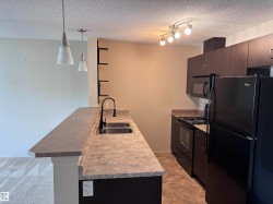 Kitchen featuring dark wood-finish cabinetry, black appliances including a refrigerator, range, and microwave, and track lighting - 