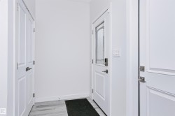 Entryway featuring a white paneled door with decorative glass insert, light gray wood-finish flooring, and crisp white walls - 