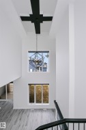 Two-story entry featuring a geometric chandelier, high windows, and light wood-finish flooring - 