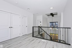 Upper-level landing featuring light wood-finish flooring and a black wrought iron railing - 