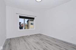 Bright room featuring light grey wood-finish flooring, white baseboards, and a large window with a black roller blind - 