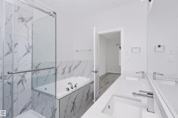 Spacious bathroom featuring a dual vanity with integrated sinks, a large soaking tub, and a separate shower enclosure with glass doors - 