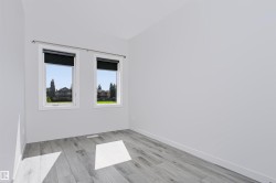 Bright interior space featuring light gray wood-finish flooring and pristine white walls - 