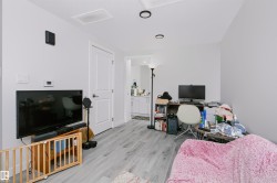 Spacious room featuring light gray walls and wood-finish flooring - 