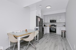 Modern kitchen featuring white shaker-style cabinetry, stainless steel appliances, light gray wood-finish flooring, white subway tile backsplash, and recessed lighting - 