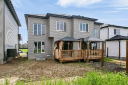 Rear exterior featuring grey horizontal siding, multiple windows, and a multi-level wooden deck with two integrated gazebos - 