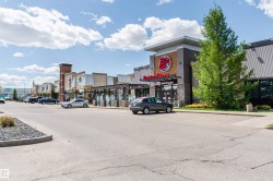 Retail complex featuring multiple storefronts, diverse architectural finishes, and ample surface parking - 