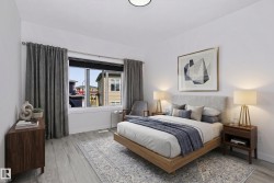 Bedroom featuring a wide window with dark blinds, light wood-finish flooring, and a contemporary ceiling light fixture - 