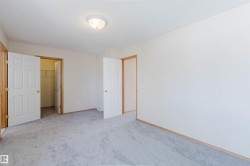 Spacious room featuring light gray carpet flooring, white walls, and wood trim - 