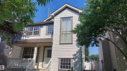 Two-story residence featuring light-colored siding, a covered front porch with white railings, and multiple windows with contrasting trim - 