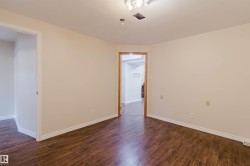 Spacious room featuring wood-finish flooring, light-toned walls, and white baseboards - 